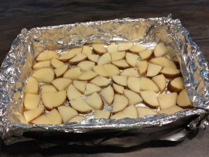 Lined pan with sliced and quartered potatoes.